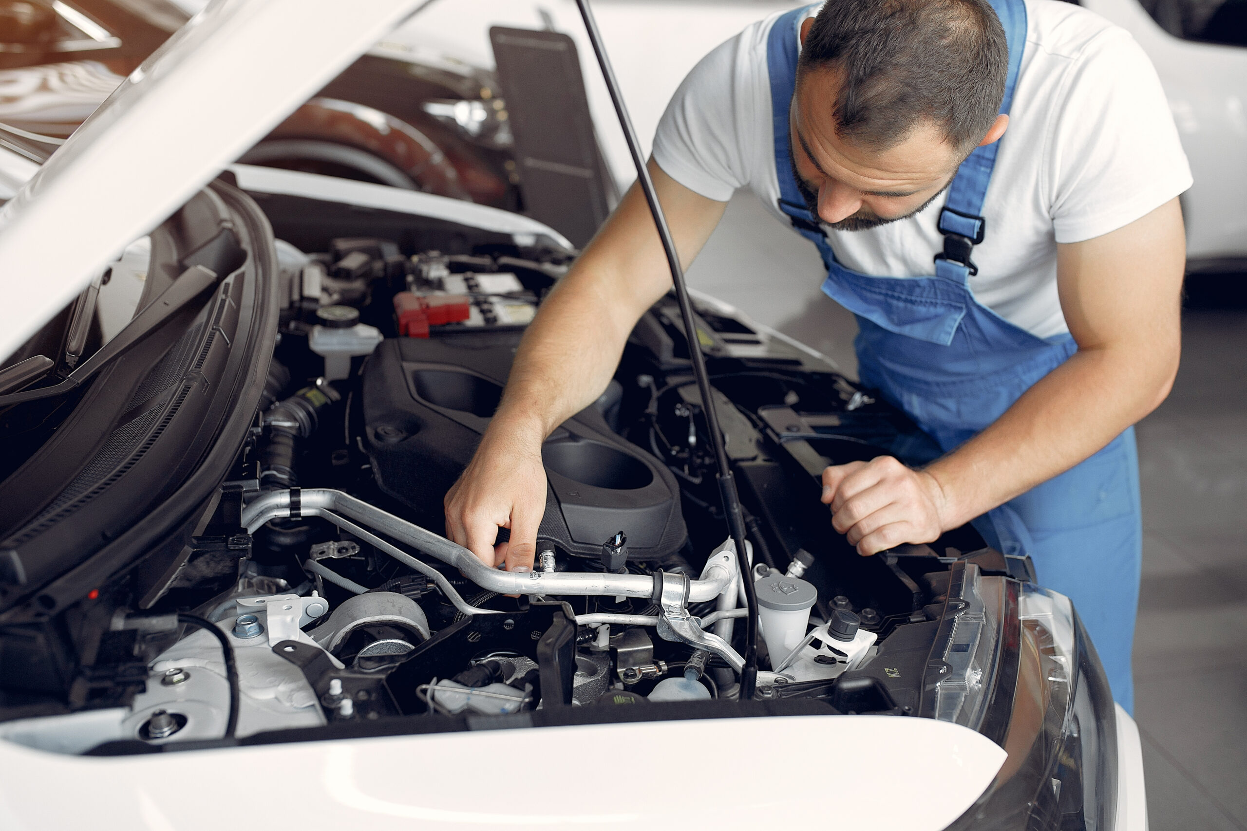 Worker in a car salon. Expert checks the car. Man in a blue uniform.